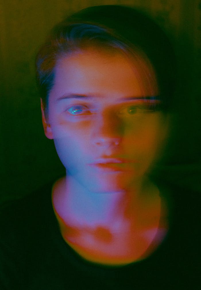 A portrait of a man under dramatic color light effects, creating a blurred artistic look.